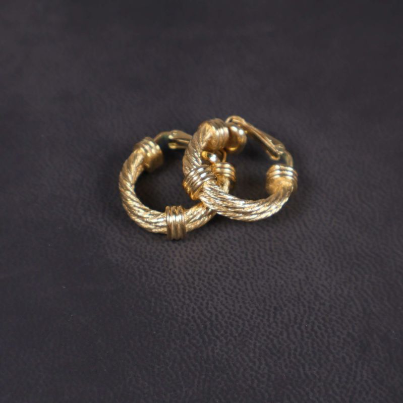 Två tvinnade guldfärgade örhängen i närbild