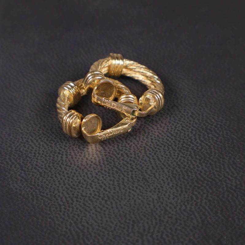 Guldfärgade örhängen liggande mot mörk bakgrund