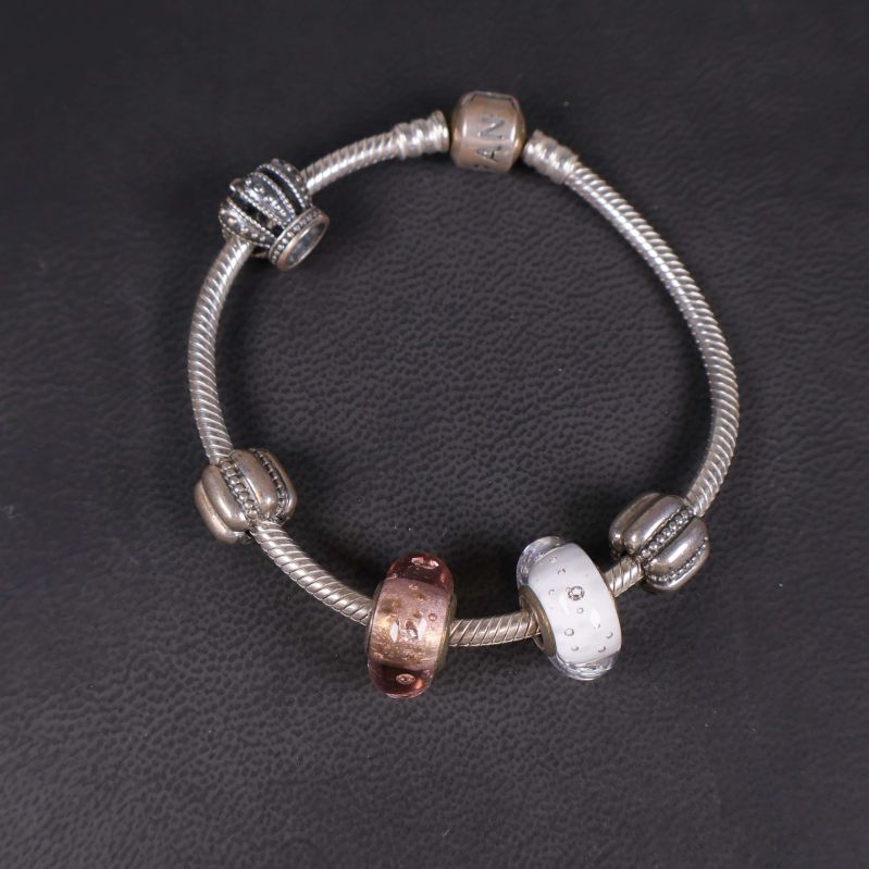 Närbild på armbandets berlocker i blandade metaller