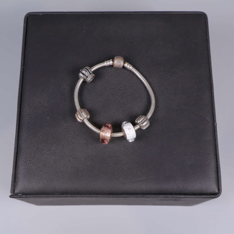 Armband med flera metallberlocker placerat på svart underlag