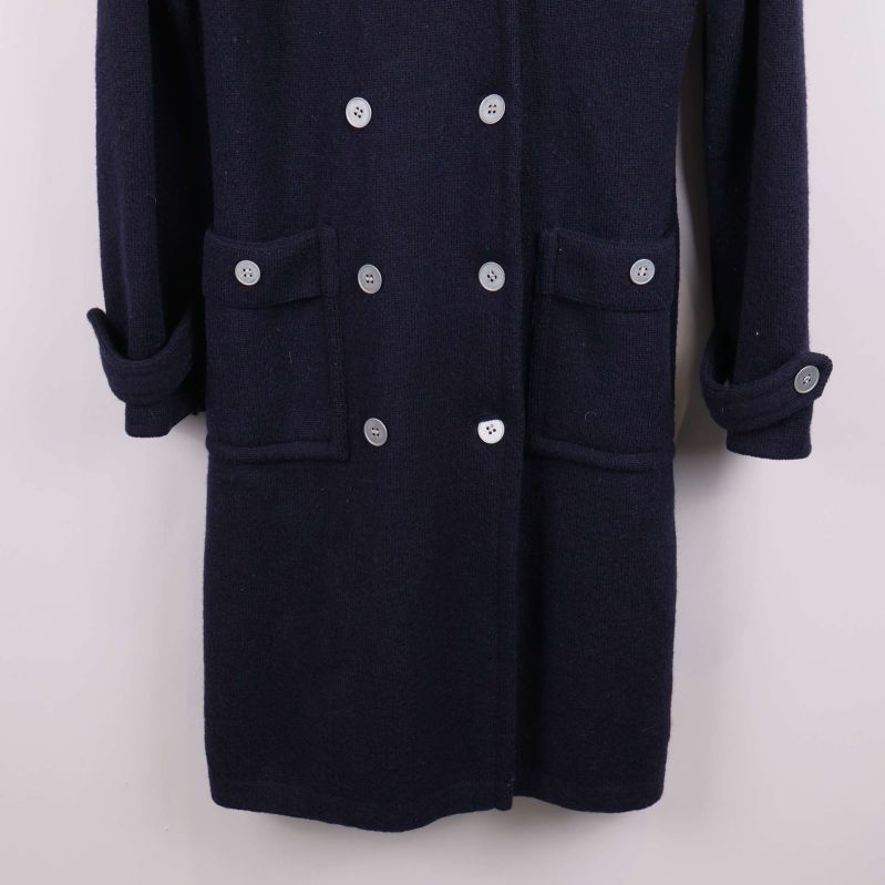 Närbild på kappa med fickor och knappar nertill