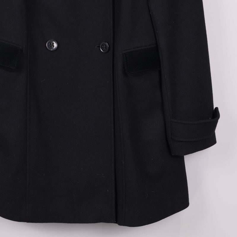 Höger ficka och ärmslut på svart kappa i närbild