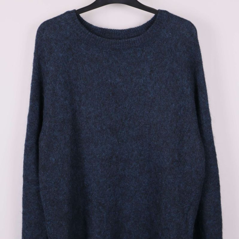 Närbild på överdelen av blå stickad tröja med rund hals