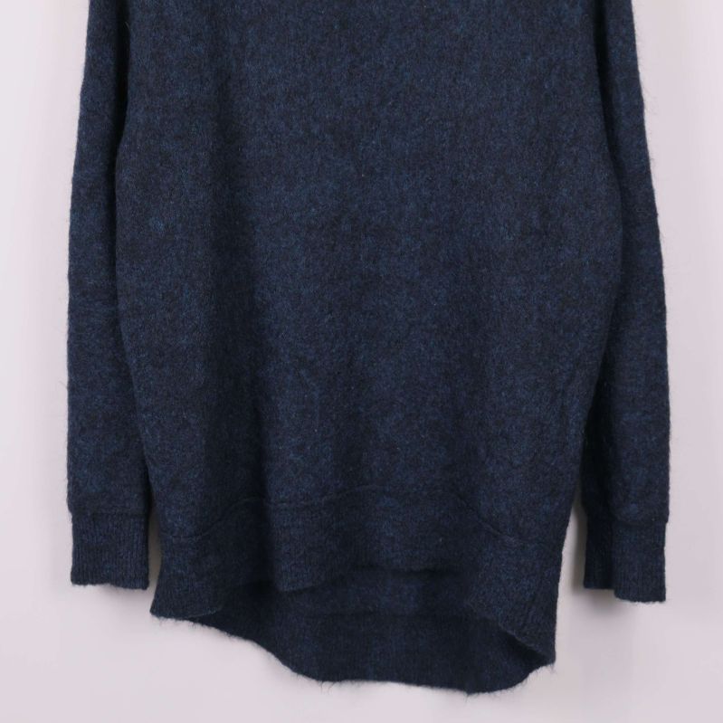 Närbild på nederkant och muddar av blå stickad tröja