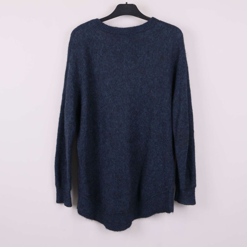 Stickad blå tröja sedd bakifrån hänger på galge