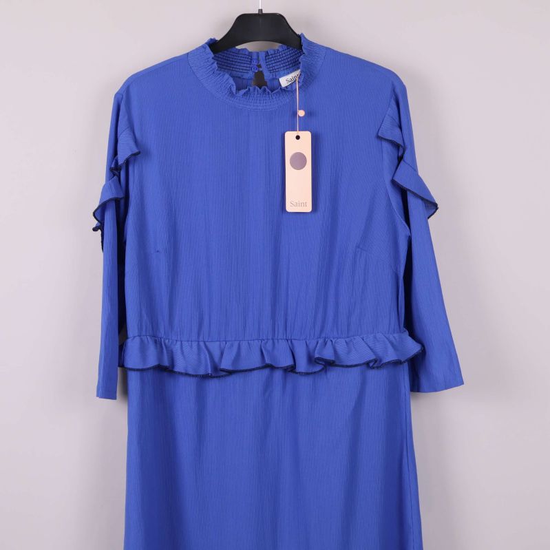 Övre del av blå klänning med volanger och etikett på galge