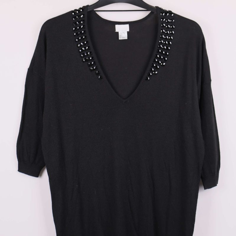 Svart tröja med dekorativa stenar visar v-ringning