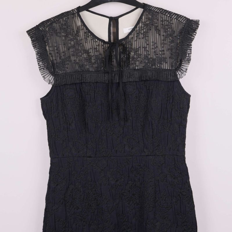 Detaljerad bild på transparent överdel och knytning vid hals på spetsklänning