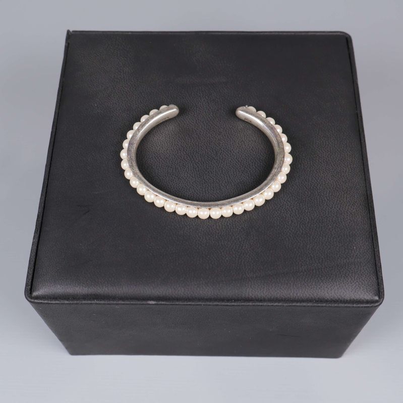 Armband med pärlor placerat på kub i svart läder