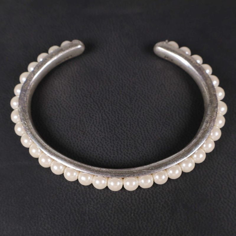 Närbild på silverfärgat armband med pärlor