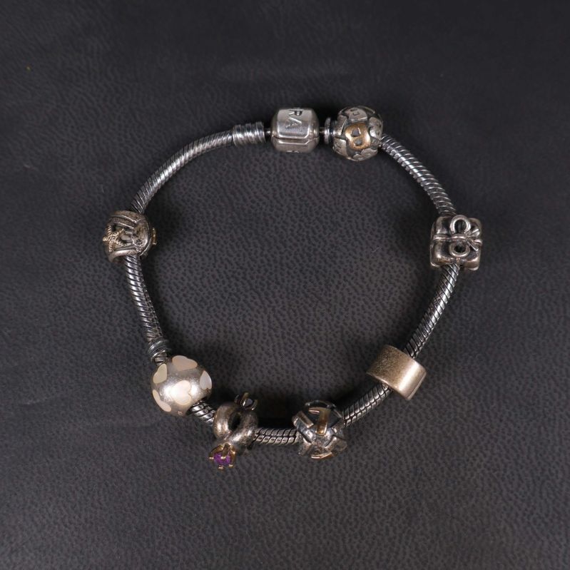 Pandora armband med berlocker liggande på svart underlag