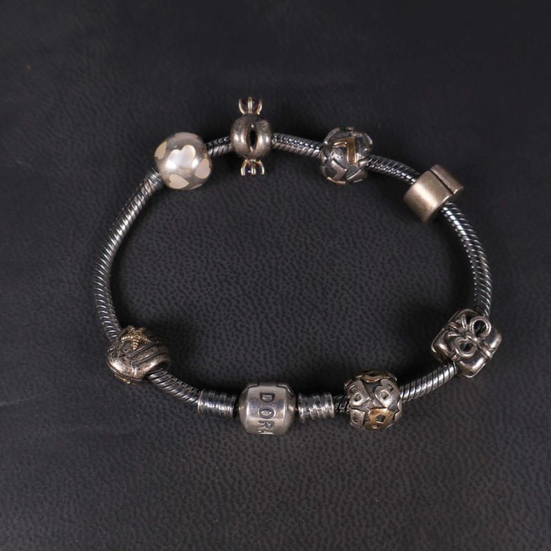 Pandora armband med berlocker liggande på svart underlag