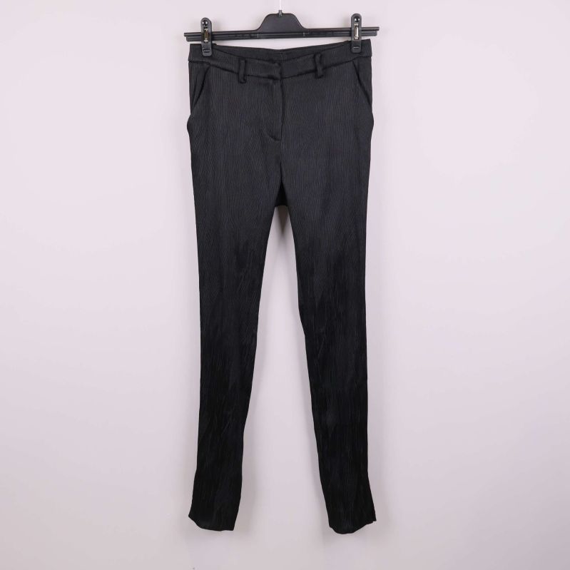 Svarta byxor med struktur hängande mot ljus bakgrund