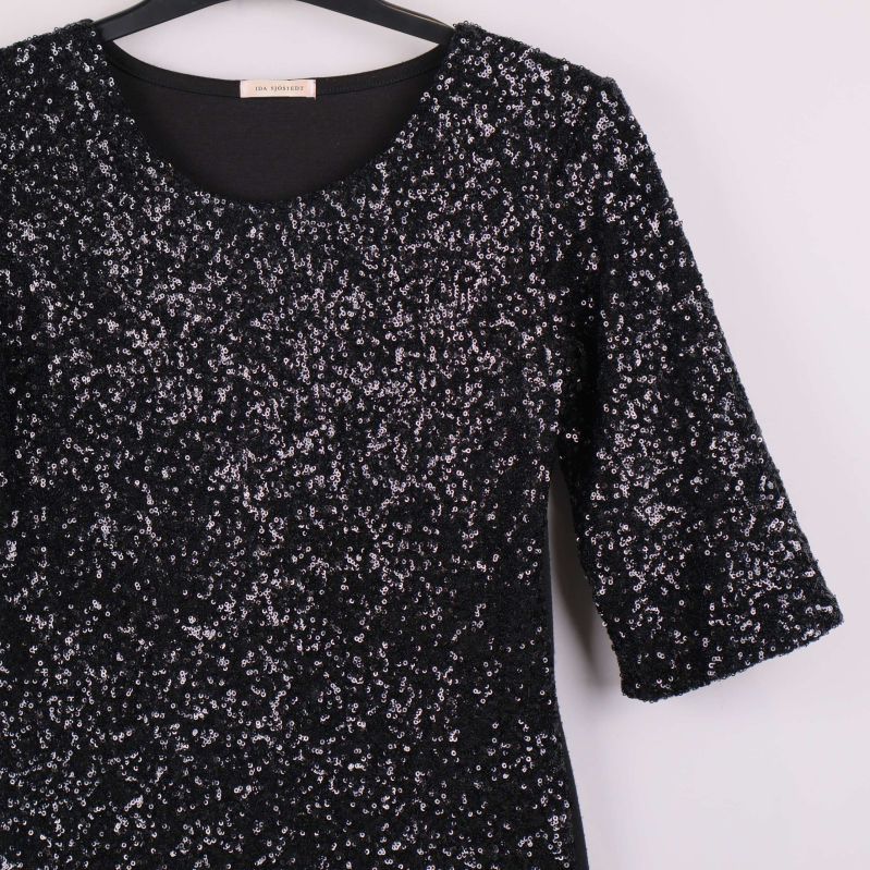 Närbild av klänningens paljettprydda framsida och trekvartsärm