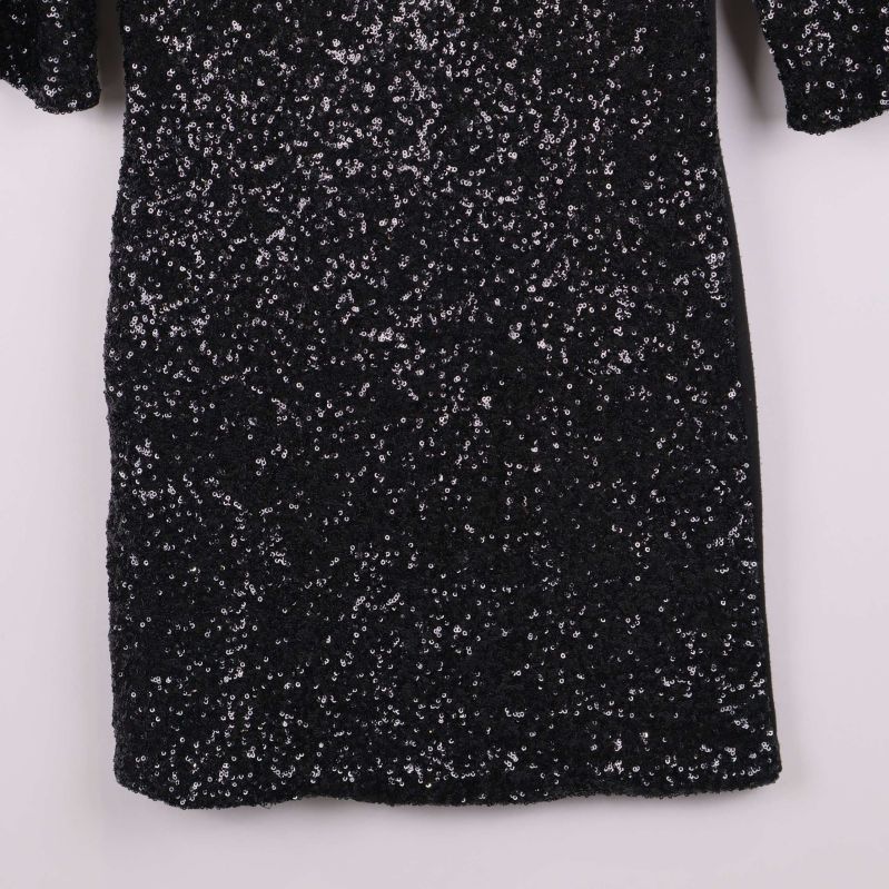 Nedre delen av svart klänning täckt av paljetter