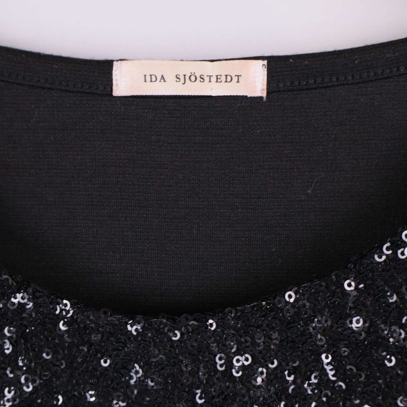 Närbild på etikett med texten 'IDA SJÖSTEDT' i kragen