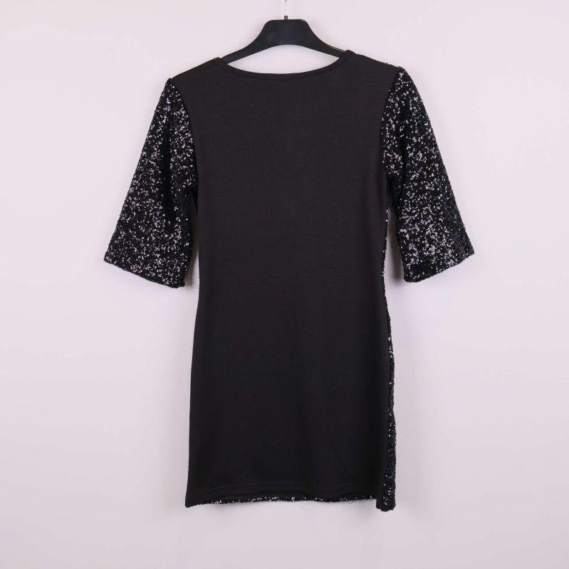 Baksidan av svart klänning med enfärgade partier och paljettärmar