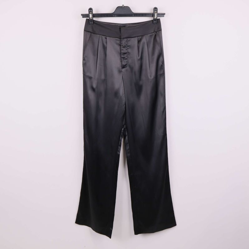 Framsida av vida svarta satinbyxor på galge