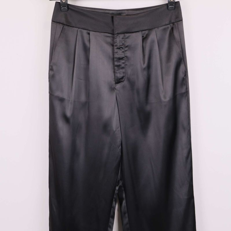 Närbild på midja och knäppning fram på svarta satinbyxor