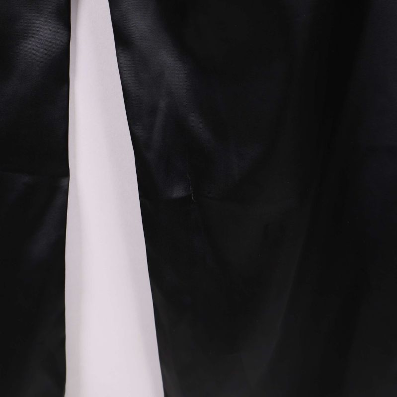 Detaljerad närbild av tyg och söm på svarta satinbyxor