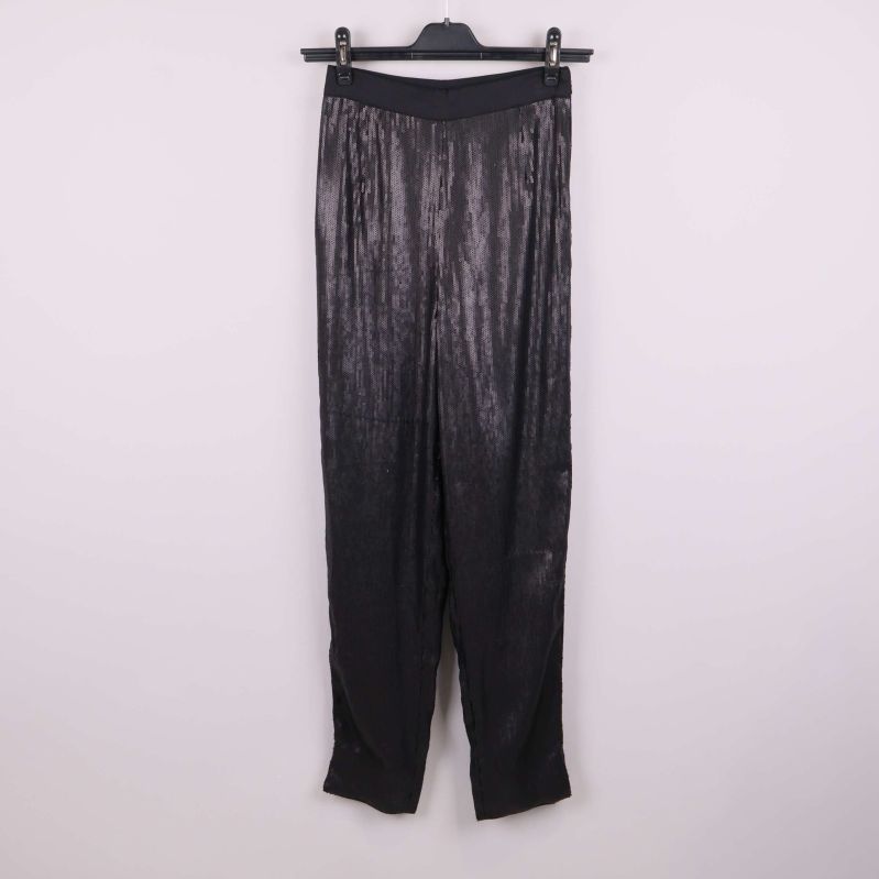 Svarta paljettbyxor hänger på galge mot ljus bakgrund