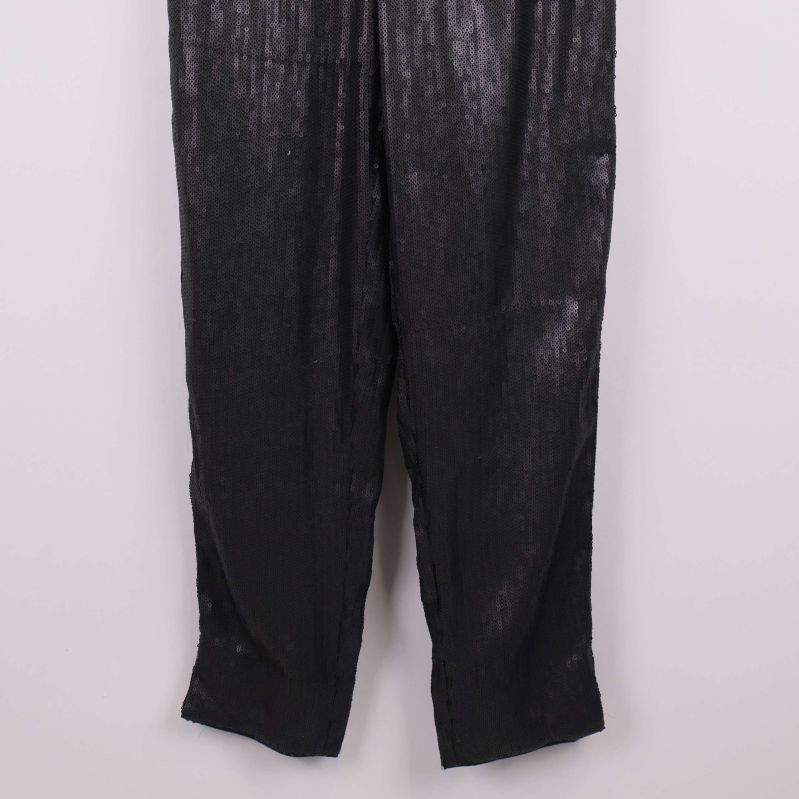 Nedre delen av svarta paljettbyxor mot ljus bakgrund