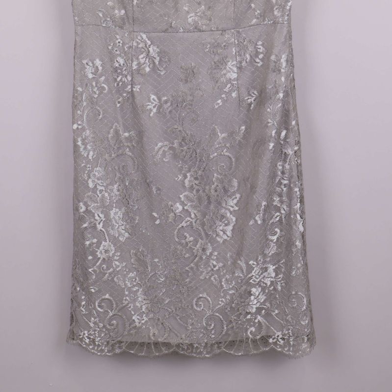 Närbild på nedre delen av silverfärgad spetsklänning