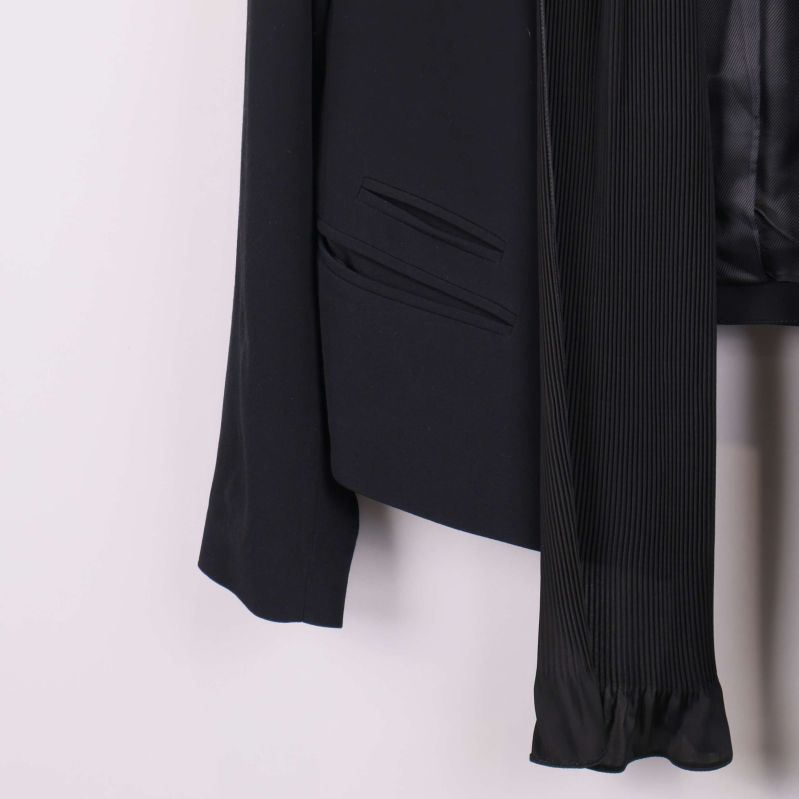 Närbild på ficka och plisserad scarfdetalj på kavaj