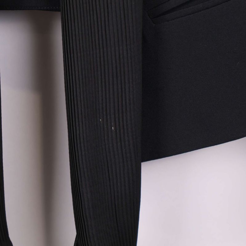 Närbild på plisserad scarfdetalj med små vita prickar