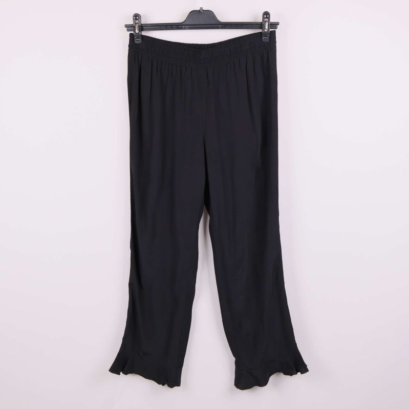 Vida svarta byxor hängande på galge med volangkant nertill