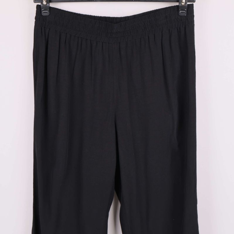 Närbild på midja och byxben för svarta vida byxor