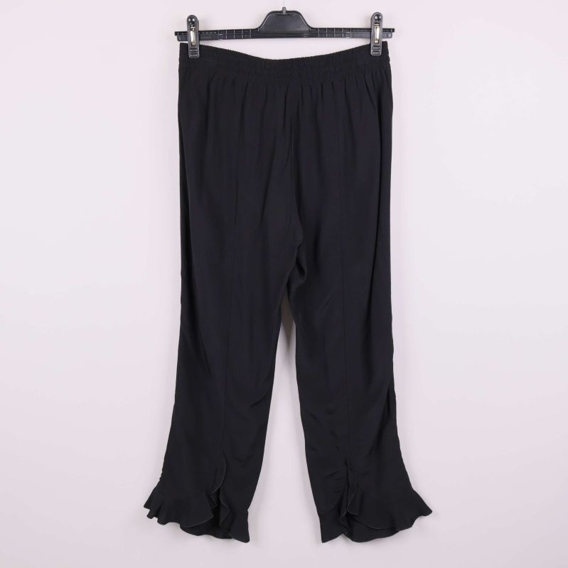 Baksidan av svarta vida byxor med volangdetalj vid foten