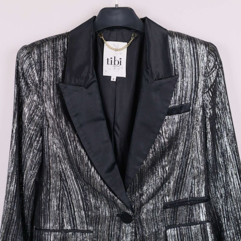 Framstycke av glittrig kavaj visar fickor och knäppning