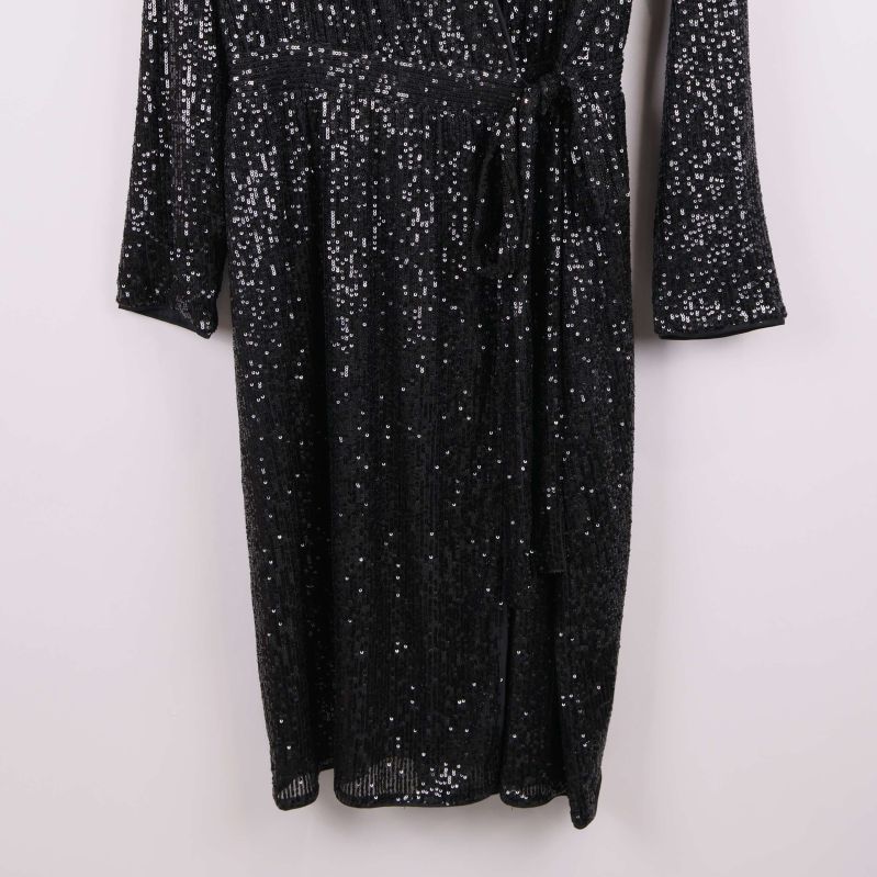 Närbild på klänningens nedre del med glänsande paljetter