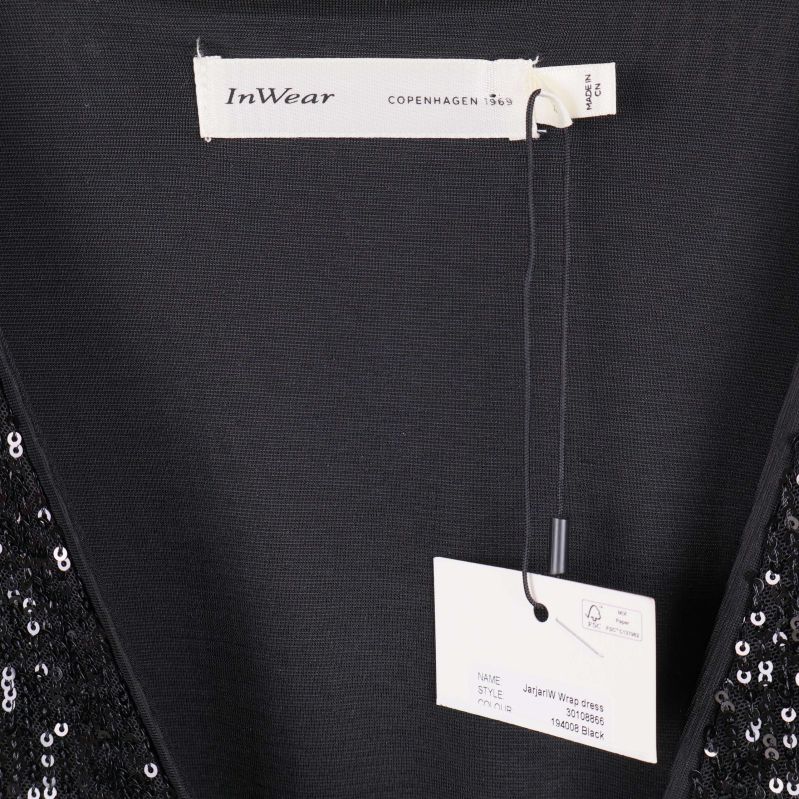 Närbild av InWear-märkesetikett och prislapp i klänningens ringning