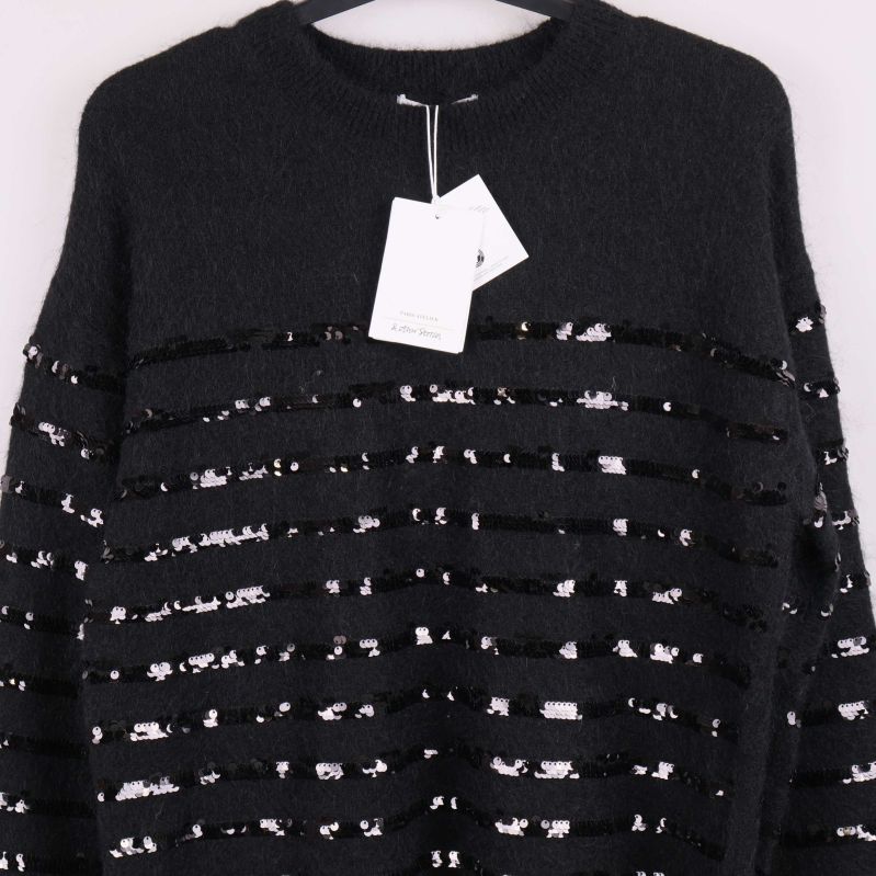 Närbild på tröjans övre del med paljettränder och etikett