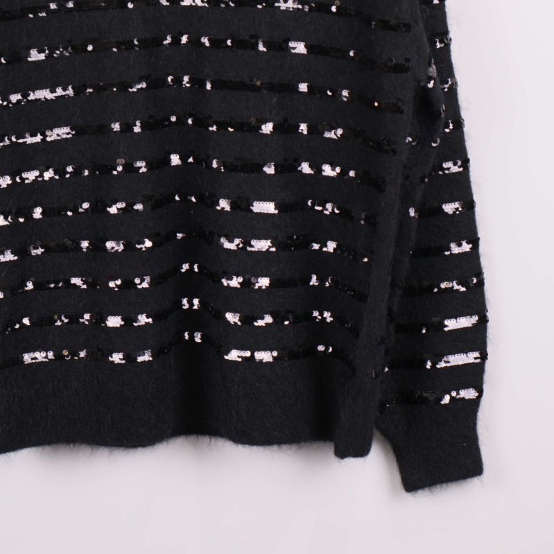 Närbild på nederdelen av svart tröja med paljettränder