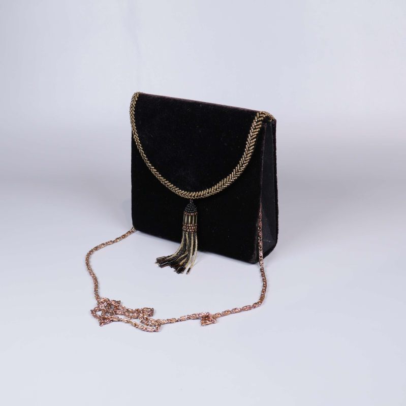 Svart sammetsväska med guldiga kedjedetaljer och hängande tofs