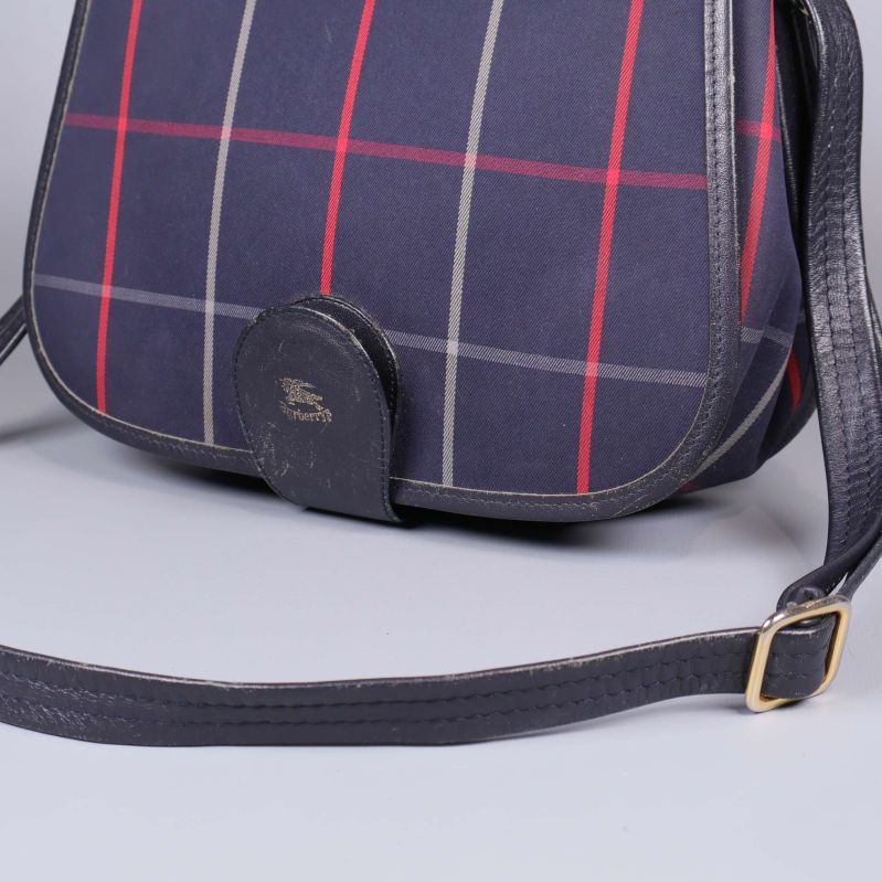 Detaljvy på väskans stängning och rutigt tyg