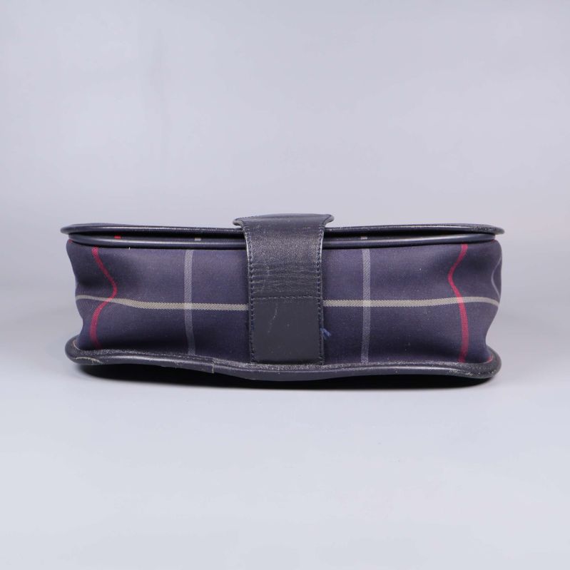 Undersida av väska med svart kant och knappdetalj