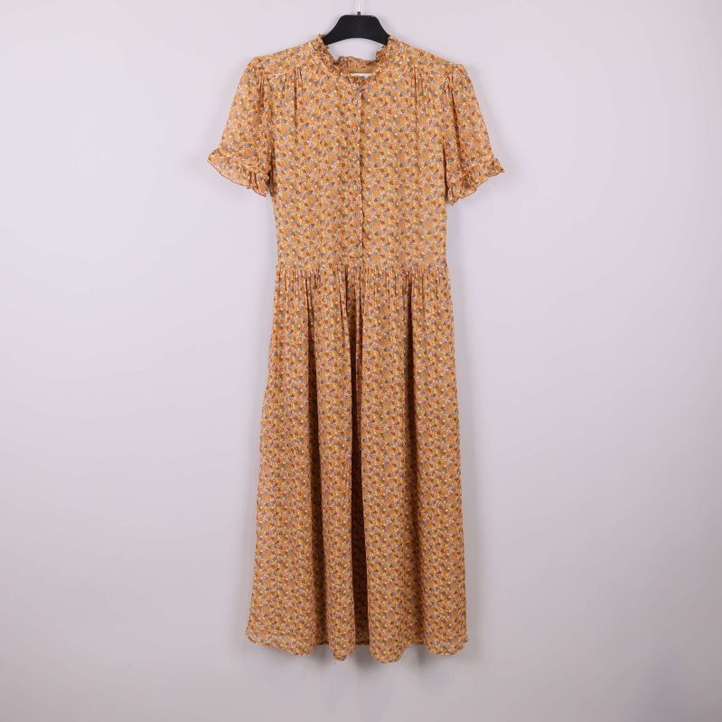 Lång blommig klänning med volanger på galge mot ljus bakgrund