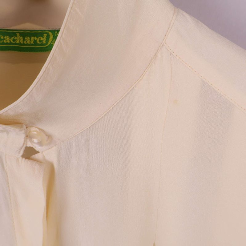 Närbild på axel och krage med pärlknapp på blus liten fläck