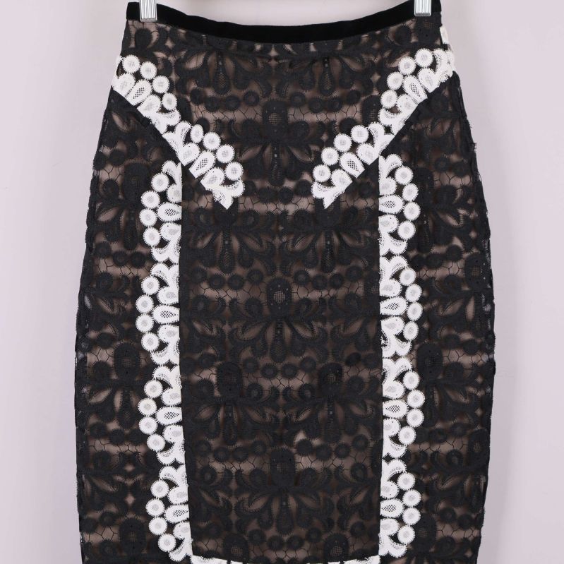 Detaljbild på överdelen av svart kjol med vita broderier