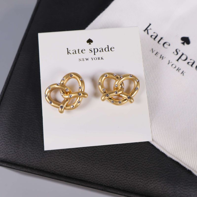 Närbild på guldfärgade örhängen i hjärtform och tygpåse