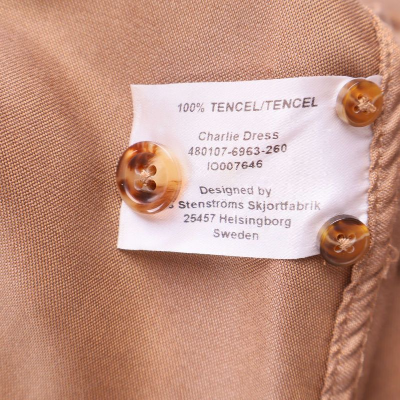 Materiallapp som visar 100% tencel och lösa knappar