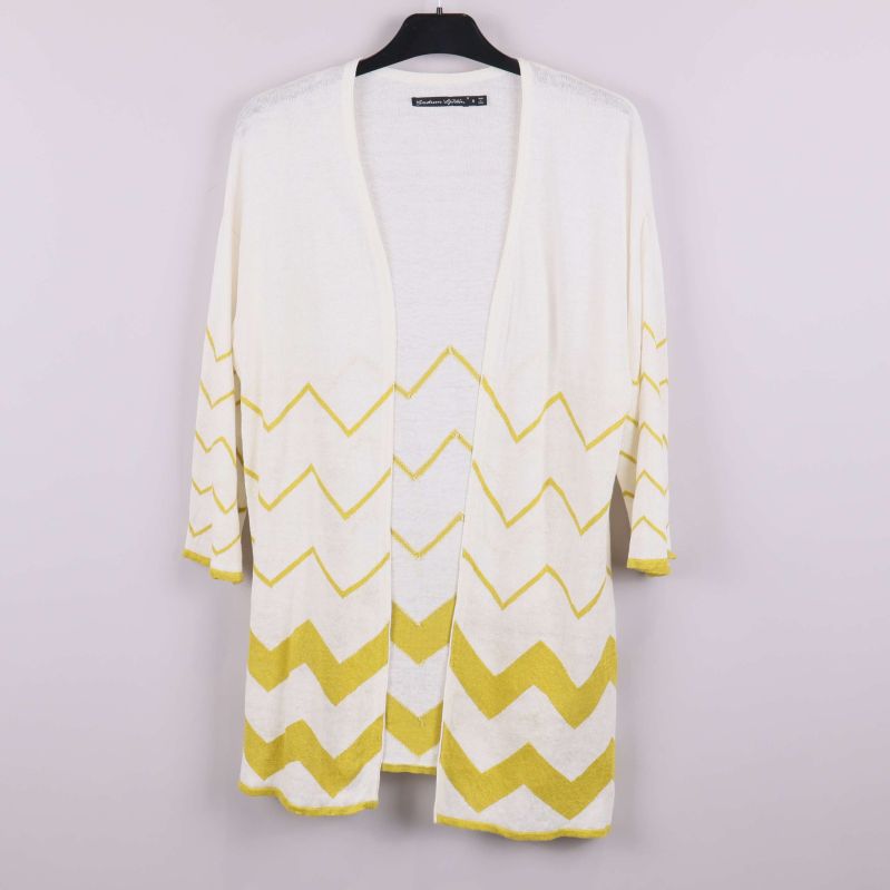 Framsida av naturvit kofta med gult zigzagmönster på galge