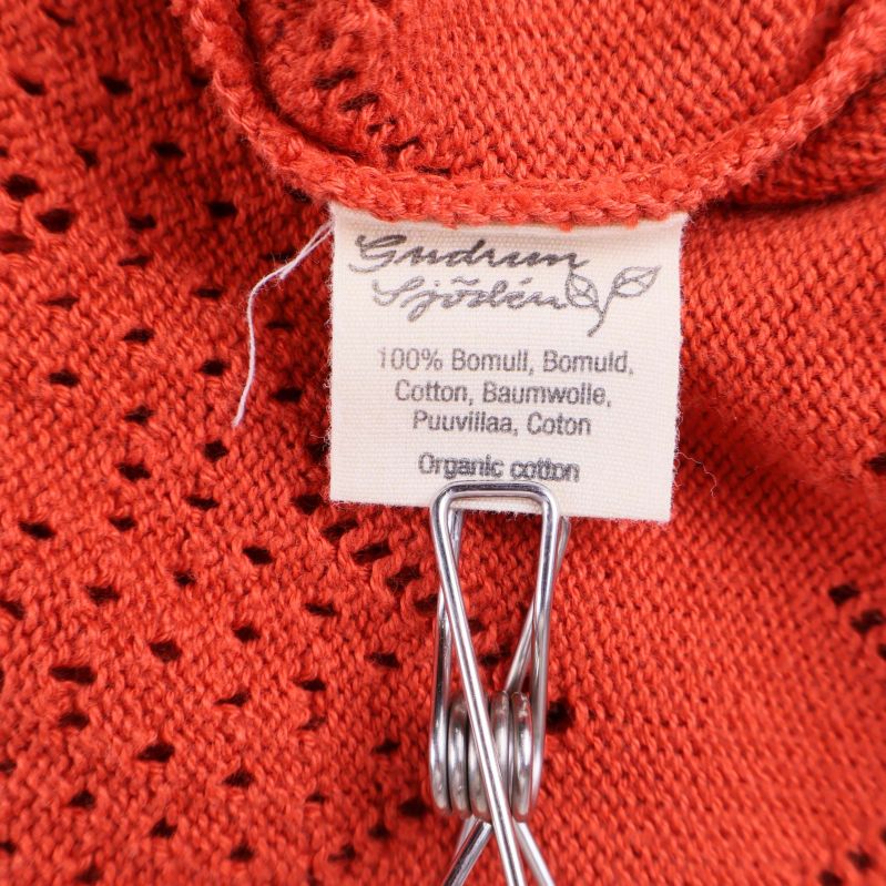 Materialetikett som visar 100% bomull på orange tyg