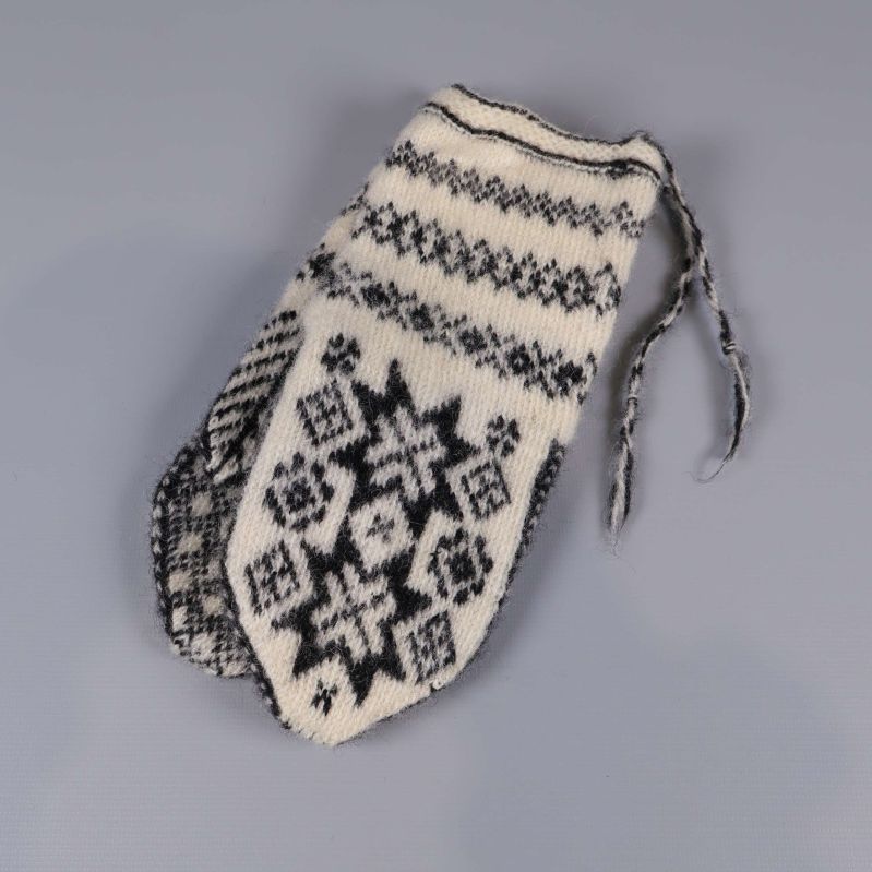 En stickad tumvante i svartvitt mönster ovanifrån