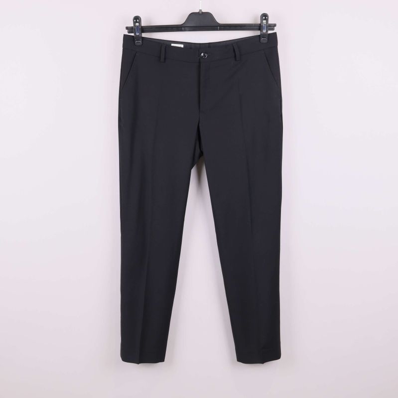 Svarta raka byxor på galge mot vit bakgrund