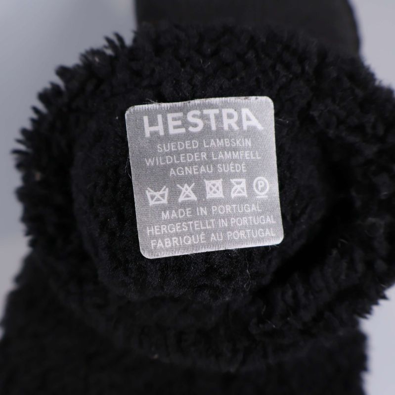 Närbild på materialetikett inuti svart vante från Hestra